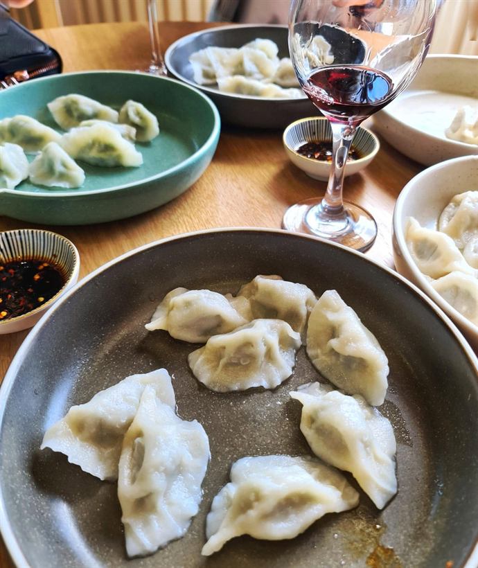 Plates of dumplings and a glass of red wine